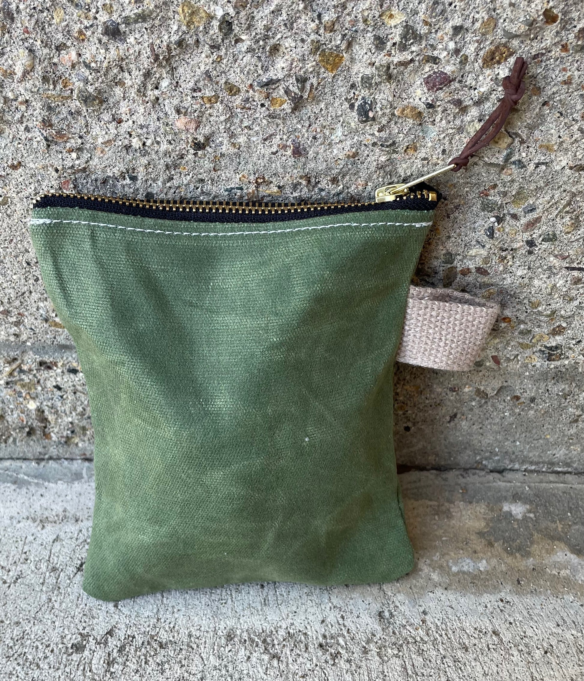 Rear view of a small ditty bag made of waxed canvas with a small handle.