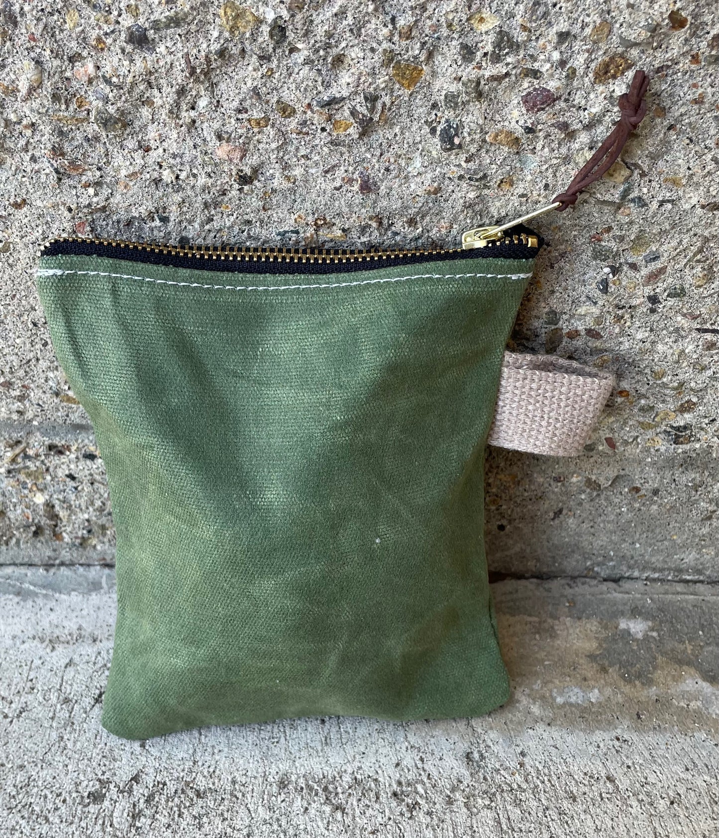 Rear view of a small ditty bag made of waxed canvas with a small handle.