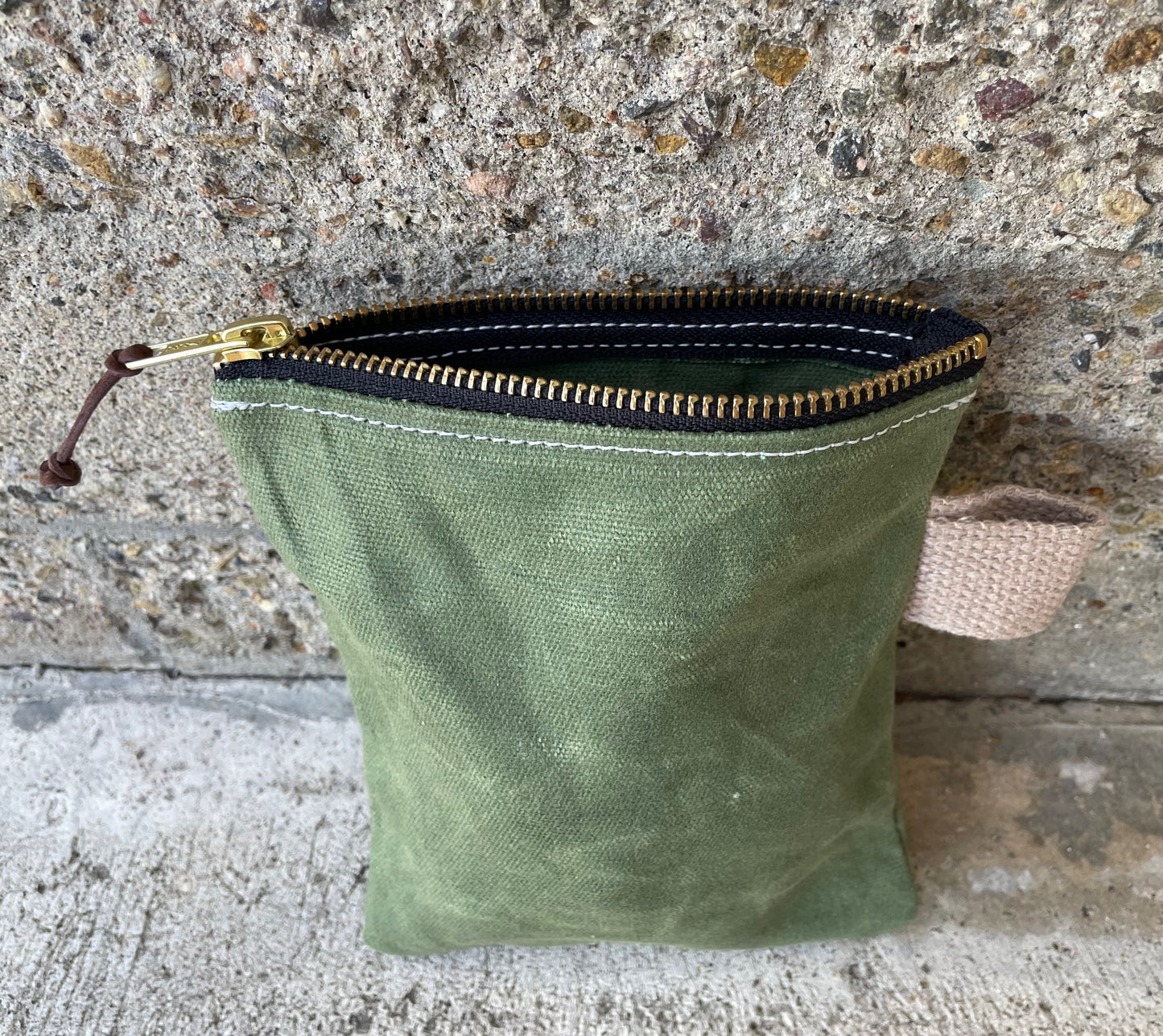 above view of a small ditty bag made of waxed canvas with a small handle. 
