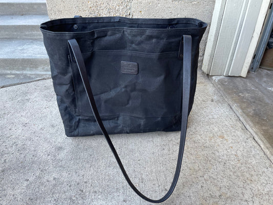 A front view of the waxed canvas market tote in the limited edition blackout color. 