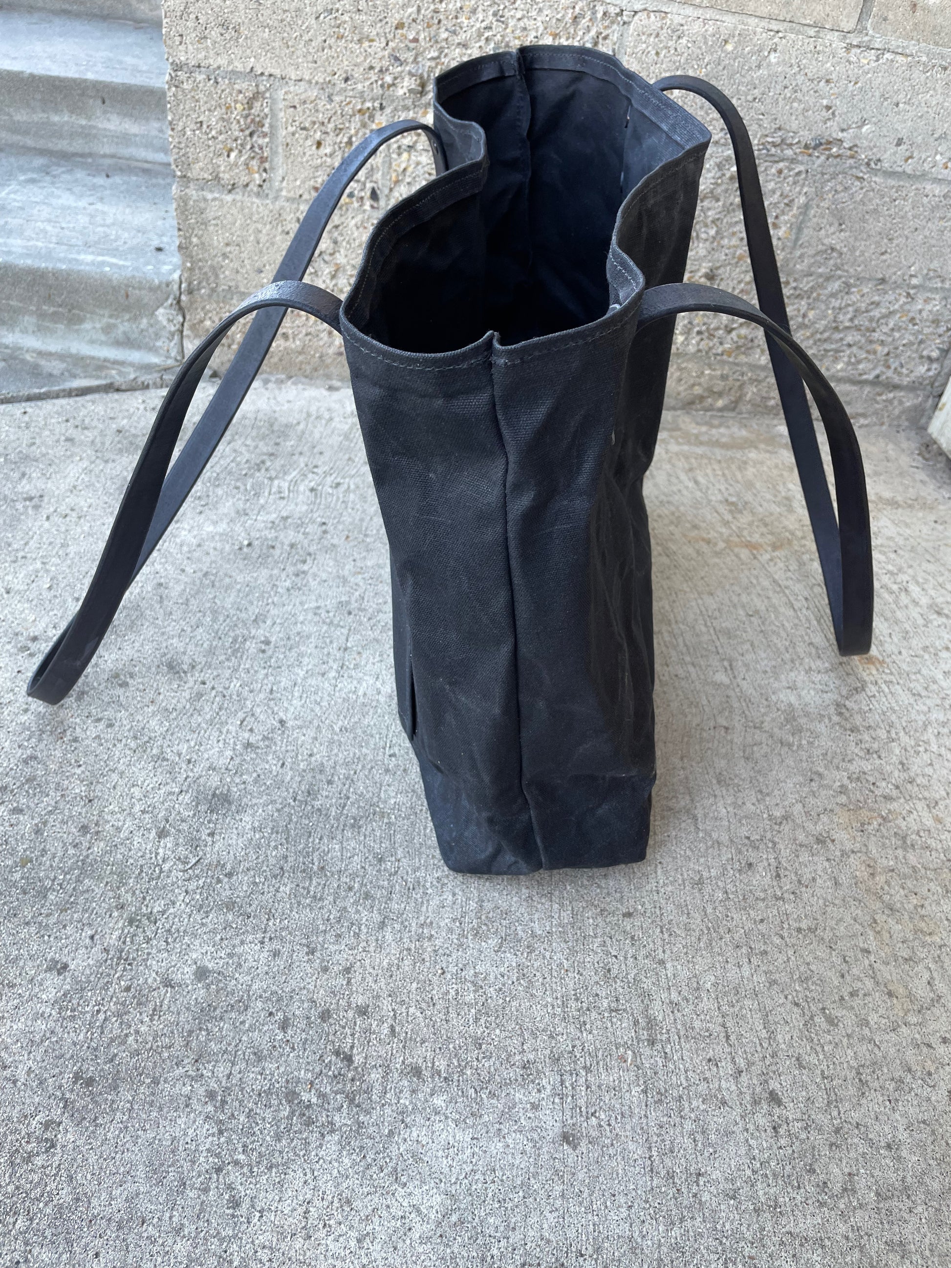 Side view of the waxed canvas market tote in the blackout colorway. 